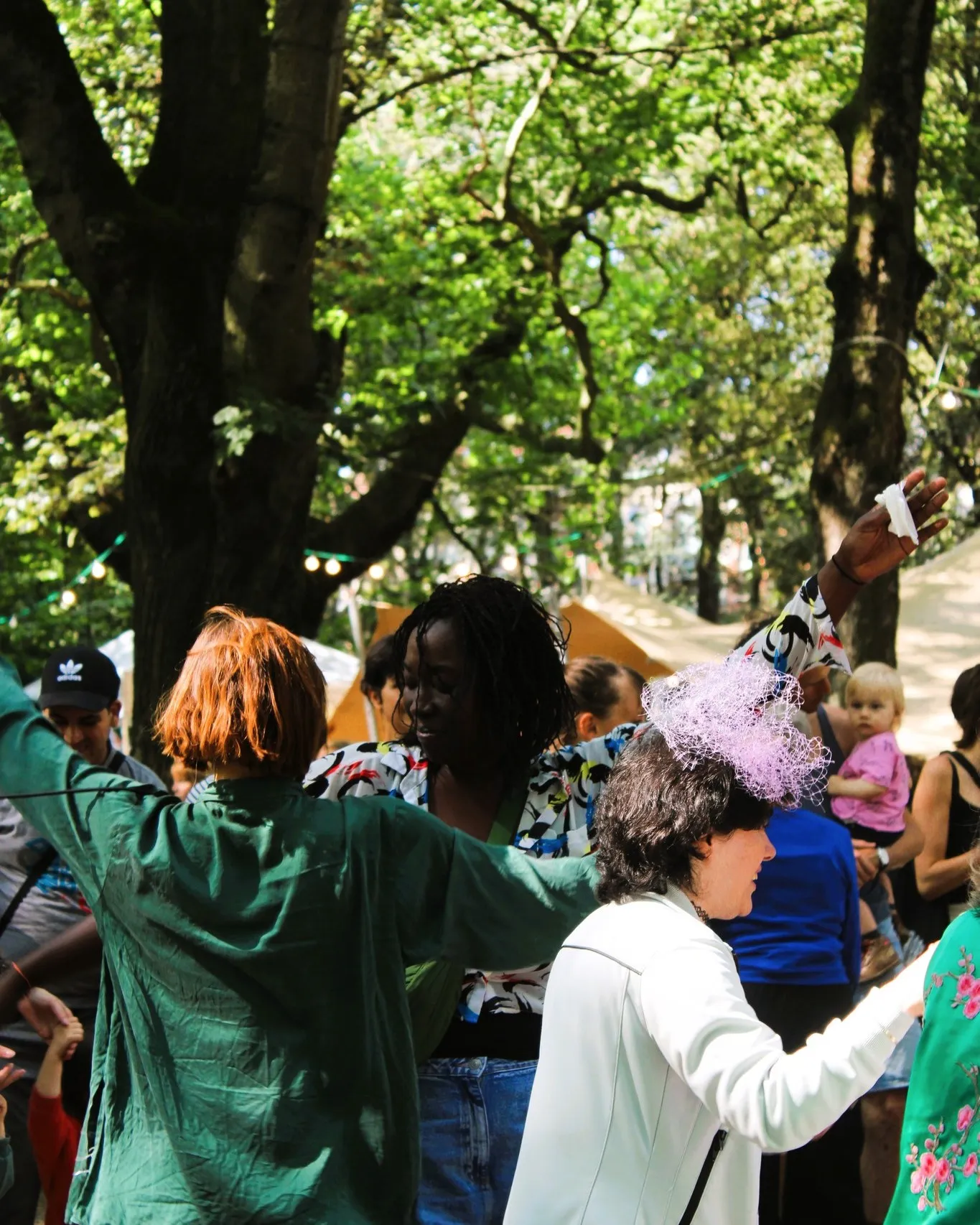 Mensen dansen buiten tussen de bomen in het Elisabethpark, verschillende leeftijden, feestelijke sfeer.