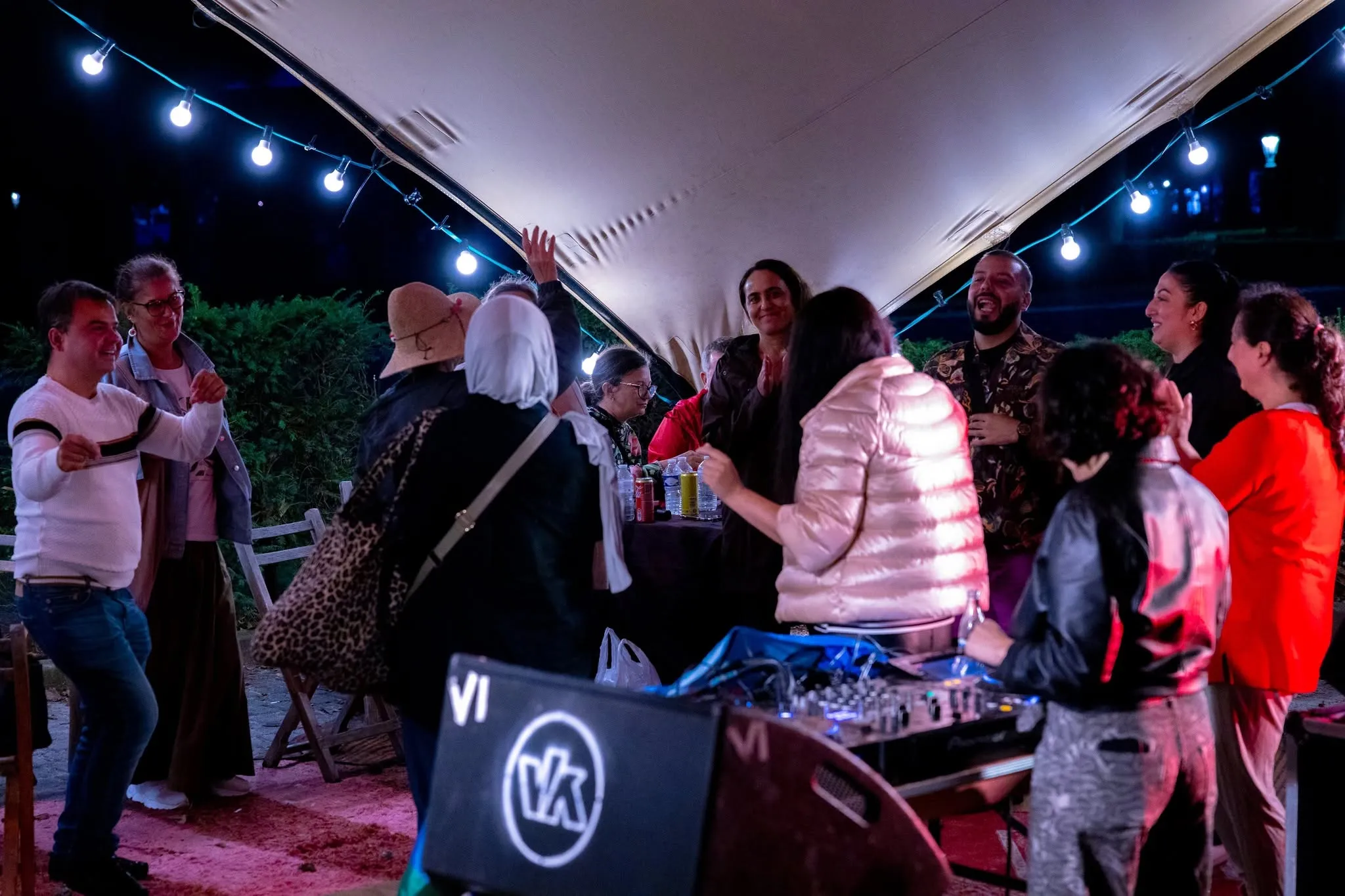 Mensen dansen onder de lichtjes bij de dj-booth, laat op de avond.